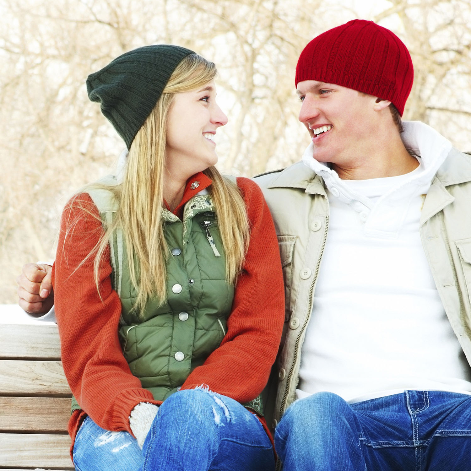 Portrait of a lovely young couple sitting on a bench outdoors during winter season